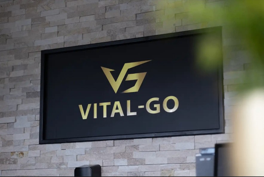 Het gouden Vital-GO-logo aan de wand van de ontvangstruimte.